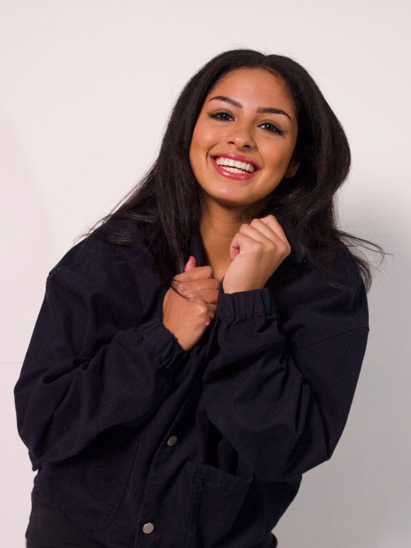 Noelani Barclay smiling in a black jacket against a soft pink wall